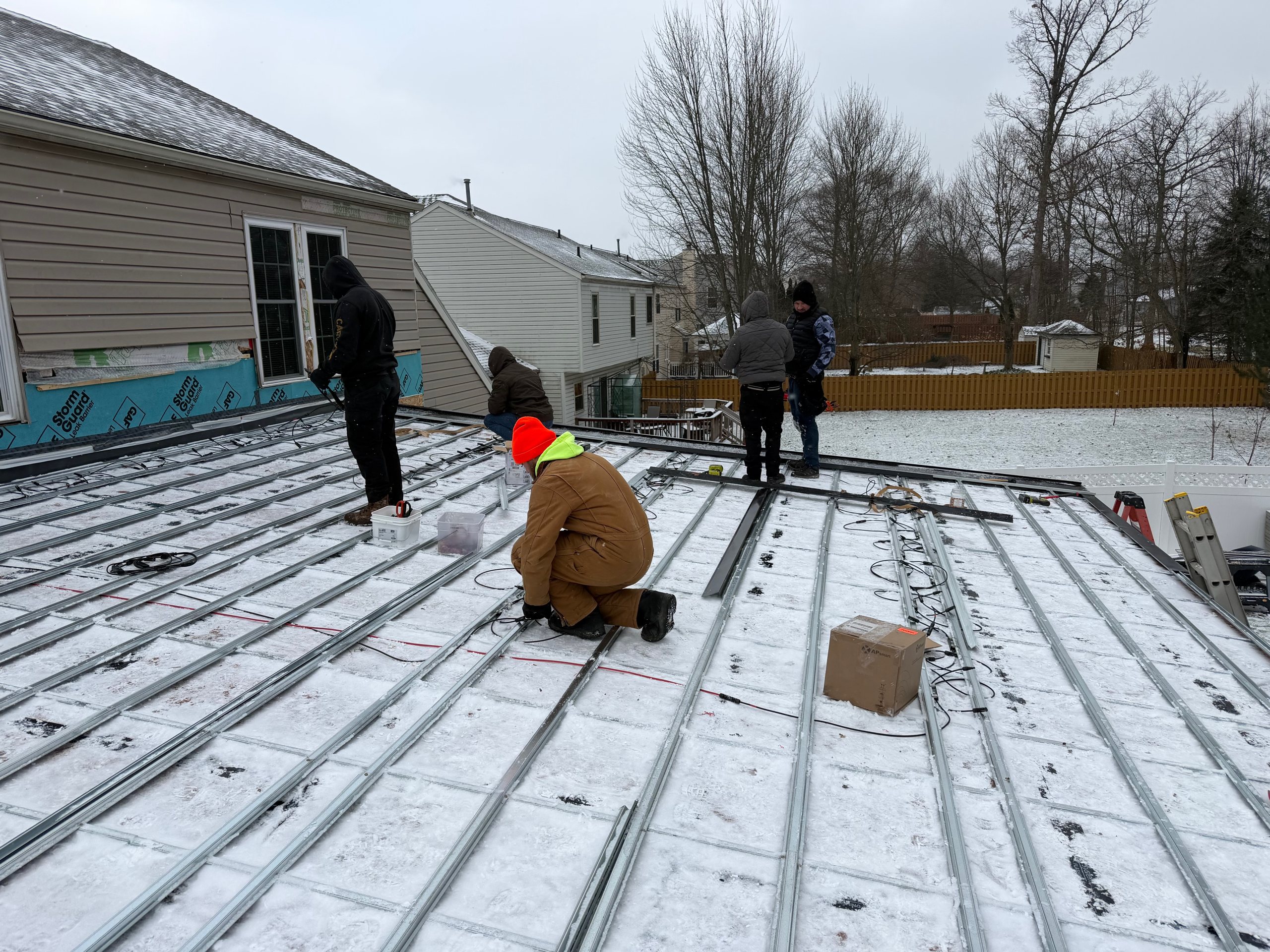 ArcEdge crew installing solar roof panels on a snow-covered American roof