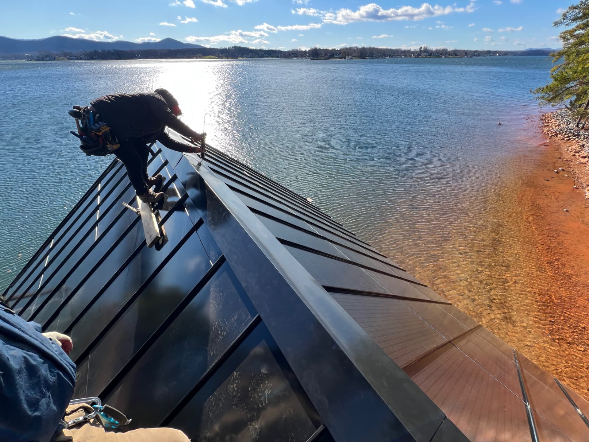 ArcEdge installer seaming integrated solar panels above Smith Mountain Lake, Virginia