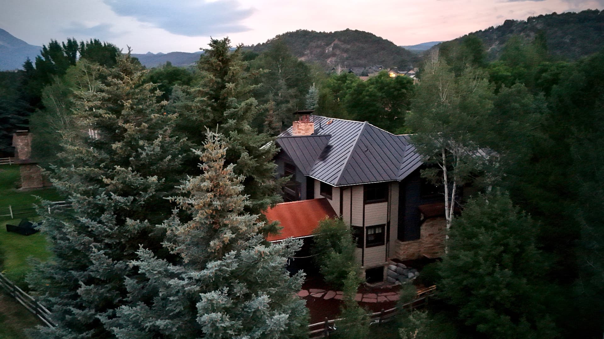 Mountain home in Carbondale, Colorado at dusk with a black integrated solar roof blending into the treeline